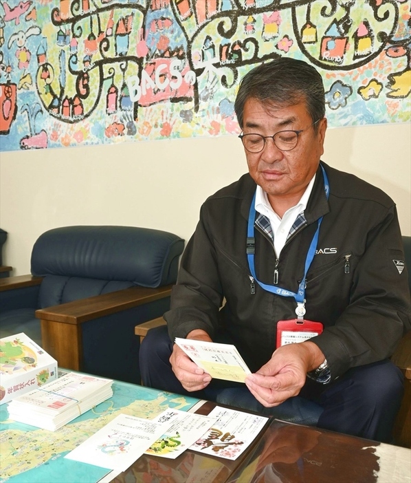 今年初めに受け取った年賀状を見返す鈴木さん。会社としては送付をやめるが、個人では続ける予定だ