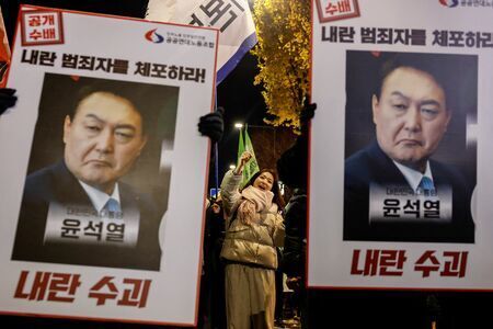 12月5日、韓国・ソウルで、尹錫悦大統領の突然の戒厳令宣言を非難し、辞任を求めるろうそく集会でプラカードを掲げるデモ参加者たち（写真：ロイター/アフロ）