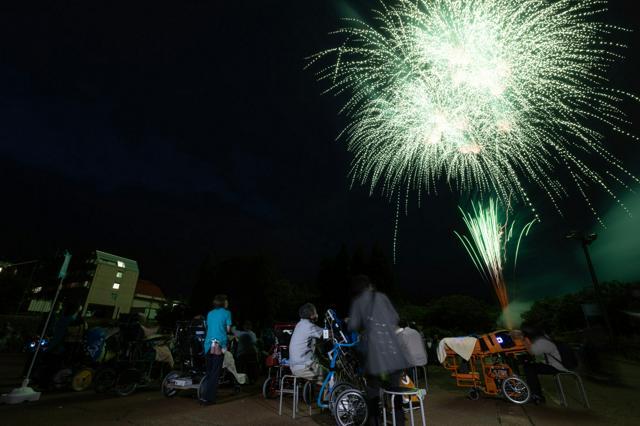 花火を見上げる利用者や親たち=2024年10月5日、新潟県長岡市、友永翔大撮影