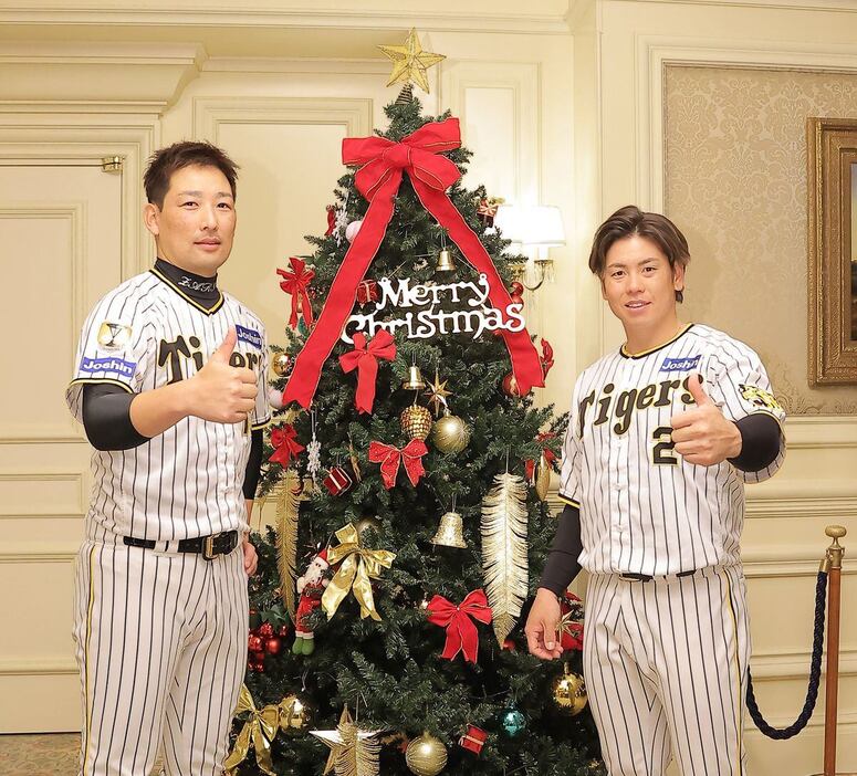 クリスマスツリーの前で記念撮影する岩崎優と梅野隆太郎＝大阪市内のホテル（撮影・根本成）