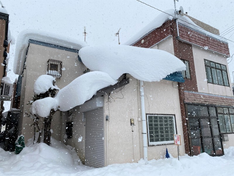 住宅の屋根からせり出す雪＝岩見沢市で2024年12月24日午後1時40分、伊藤遥撮影