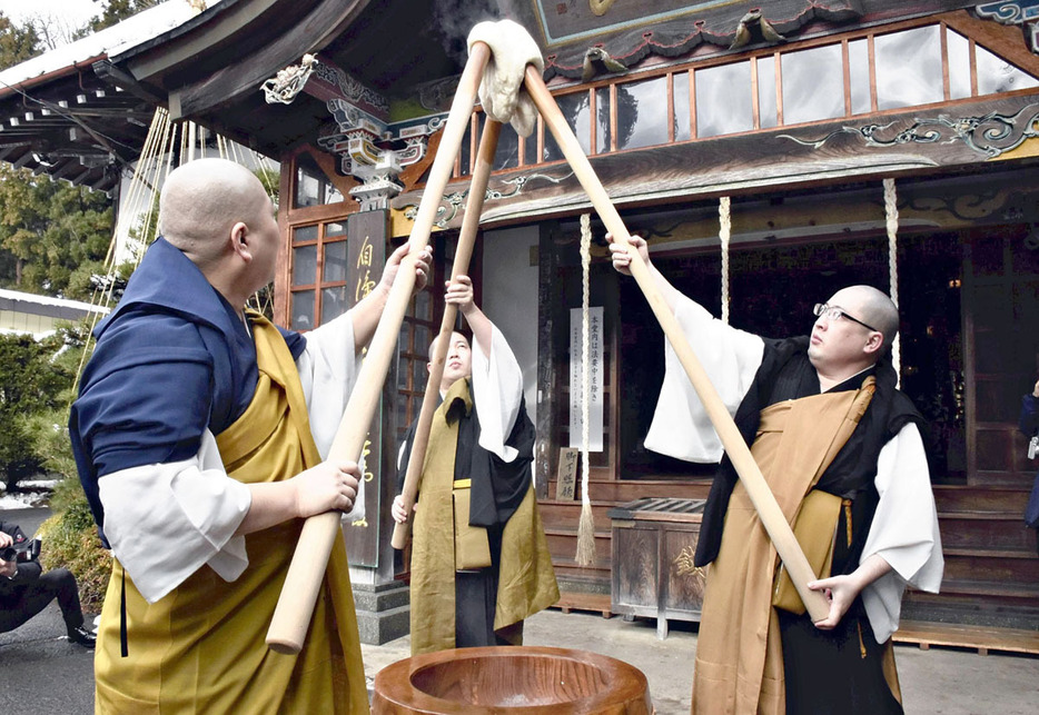 つき上げた餅を高く掲げる僧侶