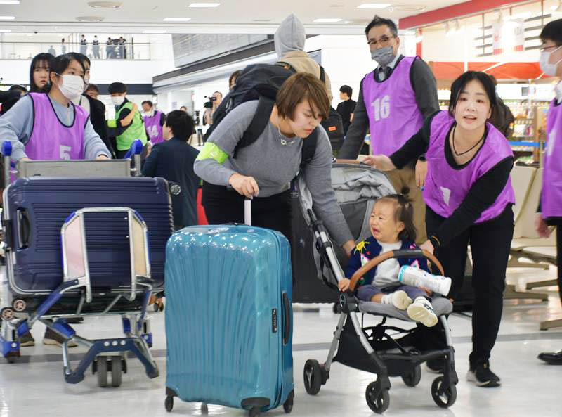 巨大地震が発生したという設定の中、成田空港でおびえる親子を誘導する訓練参加者ら＝6日、成田市