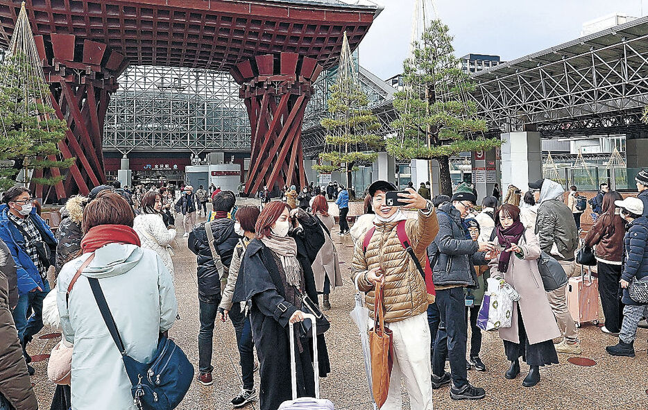 鼓門を背に記念撮影を楽しむ人たち＝金沢駅前