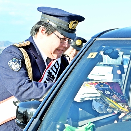 チラシを渡し飲酒運転や詐欺への注意を呼びかける山内剛店長＝島根県松江市袖師町、とるぱ駐車場