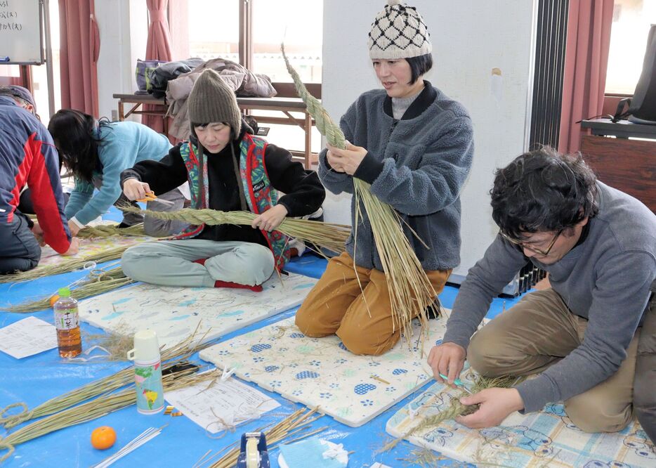 稲わらを編んでしめ飾りをつくる参加者たち（京都府京丹波町曽根・府立丹波自然運動公園）