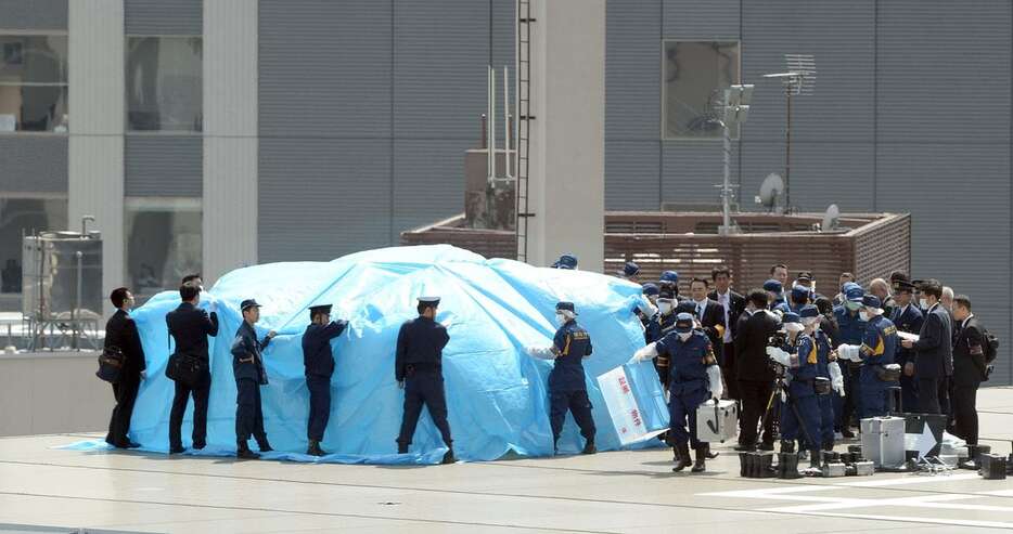 首相官邸屋上に落下したドローンを調べる捜査員ら