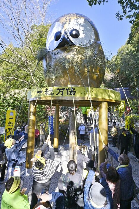 巨大フクロウ像のすすを竹で払う参拝者ら＝９日午前11時15分、那珂川町矢又