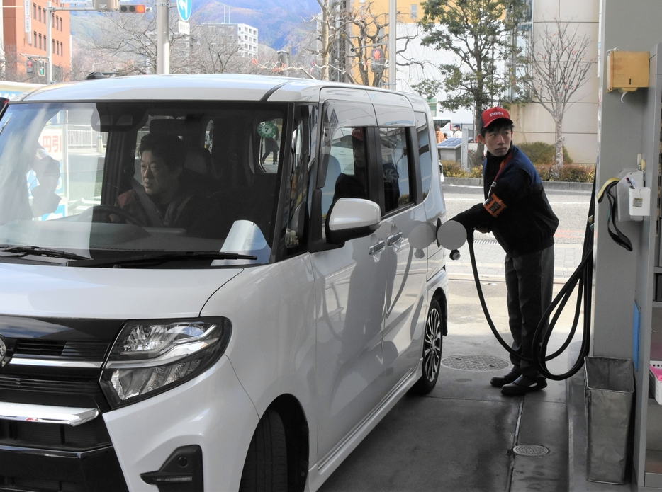 乗用車に給油するガソリンスタンドの従業員＝15日、松本市