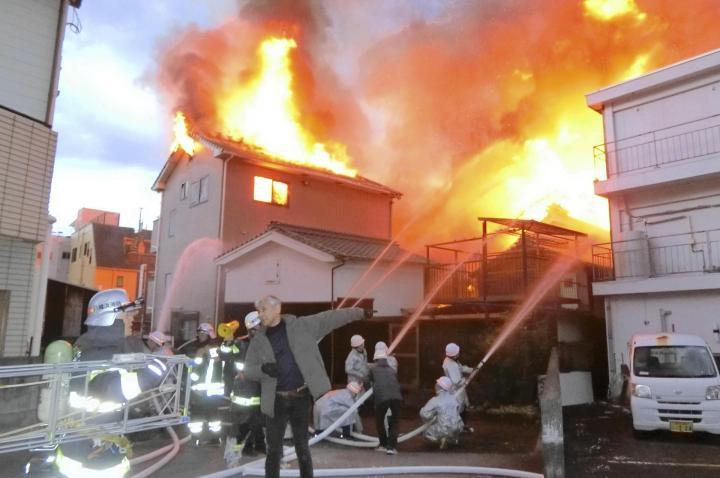 新町商店街で起きた火災で消火活動を続ける消防隊員ら＝24日午前7時10分ごろ、八幡浜市