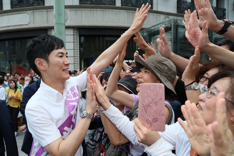 銀座四丁目交差点で街頭演説を終え、聴衆らとハイタッチを交わす前広島県安芸高田市長の石丸伸二候補（2024年6月30日、時事）