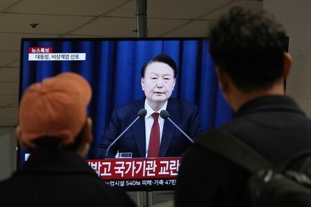 戒厳令を宣布する韓国・尹大統領のテレビ映像に見入る市民（写真：AP/アフロ）