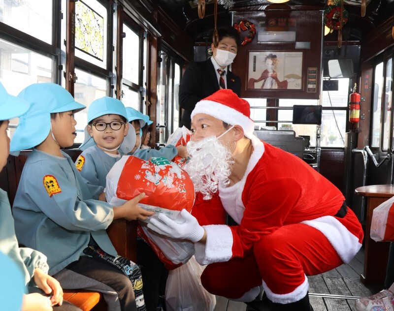 クリスマス電車の車内でプレゼントを受け取る園児ら