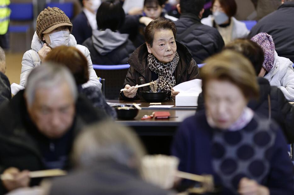 石川県七尾市の公民館で振る舞われた年越しそばを味わう人たち＝31日午後