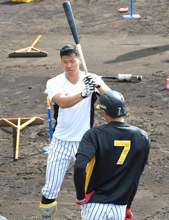 　佐藤輝のプロ１年目の春季キャンプで打撃練習中に話しかける糸井（手前）＝２０２１年２月