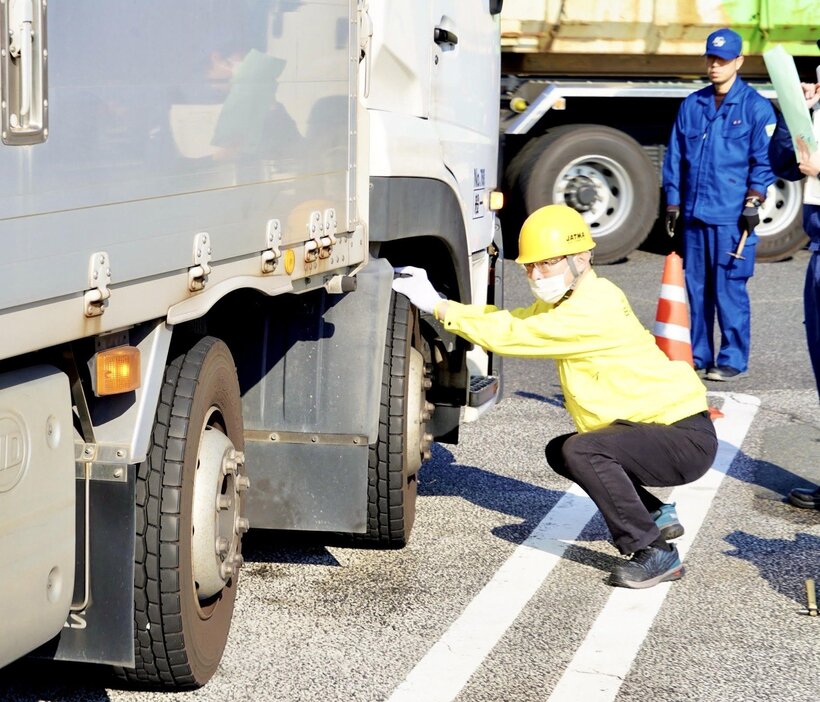 大型トラックのタイヤを点検する中国運輸局などの職員たち＝廿日市市の山陽道宮島SA（3日）