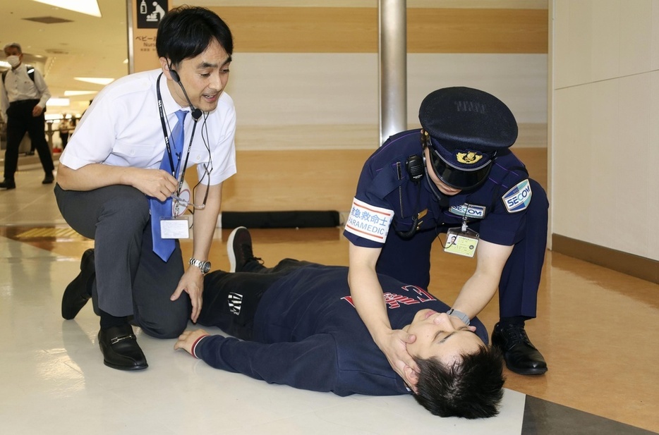 成田空港の防災訓練で、負傷した外国人旅客役の男性を手当てするセコムの救命士警備員（右）＝2024年9月