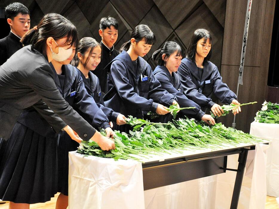 復帰運動を成した先人たちへの敬意と感謝を込めて献花する出席者＝25日、鹿児島県奄美市名瀬