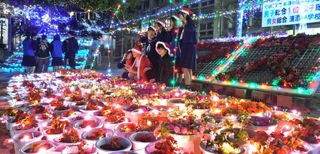 正門前の花々を照らす色鮮やかな光に笑顔を見せる生徒＝１７日、浦添中学校