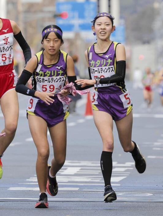 【女子】聖カタリナ学園2区の上岡紗代（右）から38位でたすきを受け取り、走り出す3区の宮脇心美＝京都市の第2中継所（撮影・中野貴衣）