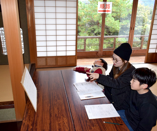 和室で座り、協力してクイズを解く親子