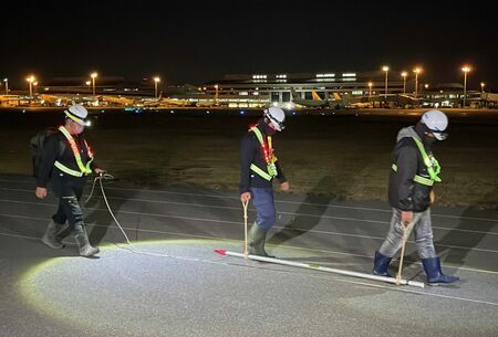 那覇空港の滑走路周辺で不発弾の磁気探査を開始する作業員ら＝１７日午後１１時５０分、那覇市