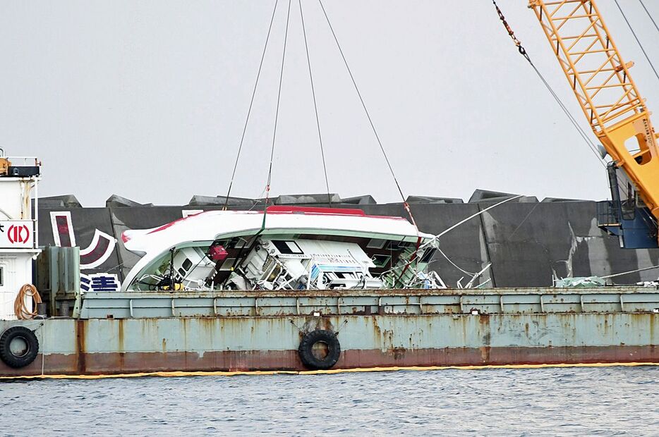 起重機船のクレーンにより傾いた状態で固定された「第28光明丸」＝22日午後、むつ市の大畑漁港