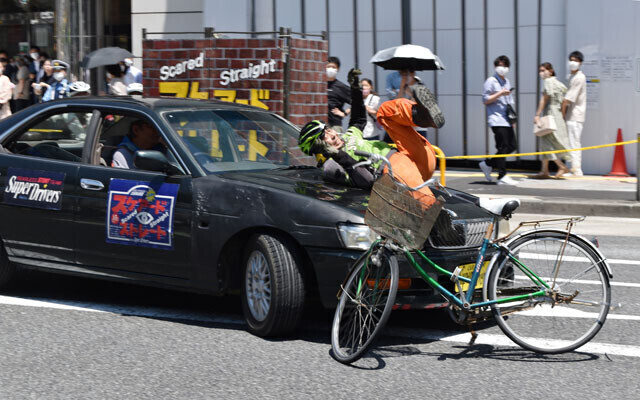 警察の交通安全イベント。ヘッドホンをしたまま自転車に乗るスタントマンがクルマに気づかず事故が起きる様子などを再現