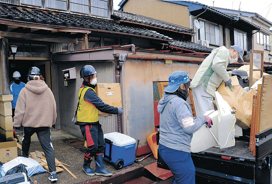 廃棄処分される家財道具を運び出すボランティア＝高岡市伏木地区