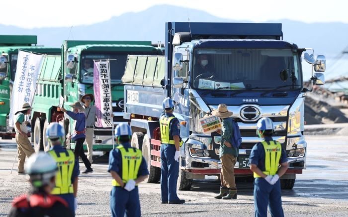 ダンプの前でメッセージを掲げ抗議する人たち＝２日午前９時4３分、本部港塩川地区（小川昌宏撮影）