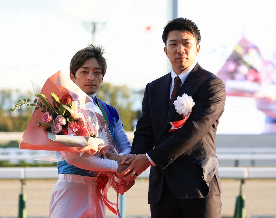 ＜京都競馬　11R・朝日杯FS＞レースを制した川田将雅騎手（左）と握手を交わす阪神・石井（撮影・中辻　颯太）