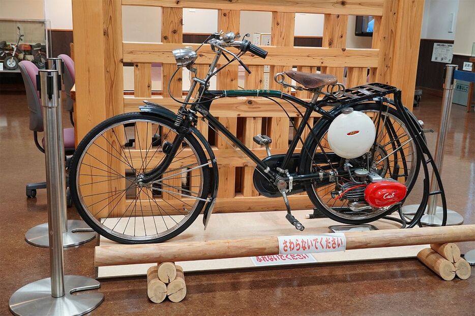 1952年にホンダが発売した自転車用補助エンジン「カブF型」。白いタンクと赤いエンジンで広く親しまれた（筆者撮影）