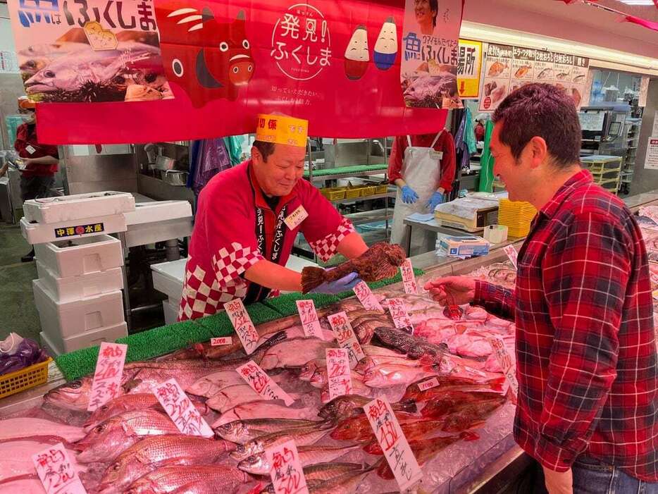 角上魚類の大宮店で開かれた福島応援フェアで、オコゼを購入する居酒屋経営の男性＝12月13日、さいたま市