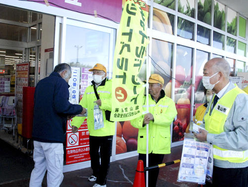 【買い物客（左端）に交通事故防止を呼びかける参加者ら＝亀山市田村町のマックスバリュ亀山みずほ台店で】