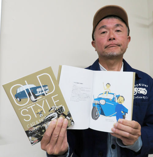 【旧車とオーナーをイラストで紹介した新刊を手にするosattoさん＝伊勢市役所で】