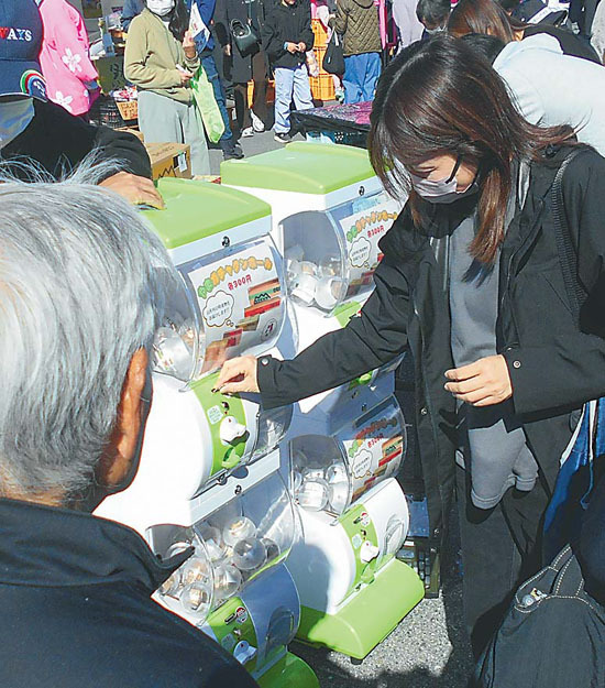 JAまつりでカプセルトイ「やまガチャ段ボール」を回す来場者ら（長野県山形村で）