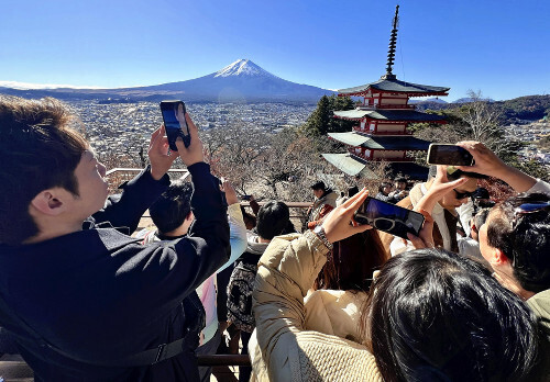 冠雪した富士山を写真に収めようと集まった大勢の外国人観光客ら（９日、富士吉田市の新倉山浅間公園で）