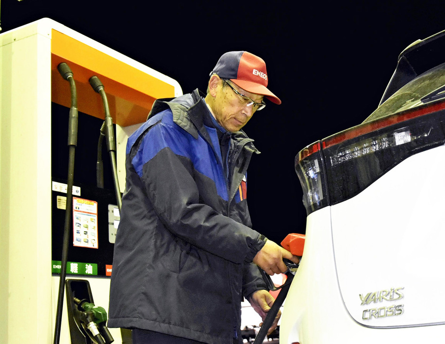 閉店間近までガソリンの給油作業に追われた岡部さん＝18日午後7時ごろ、石川町