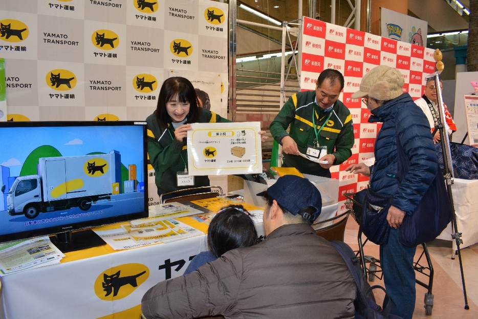 配達に関するクイズなどで、再配達削減を呼び掛ける宅配業者＝30日、八戸市