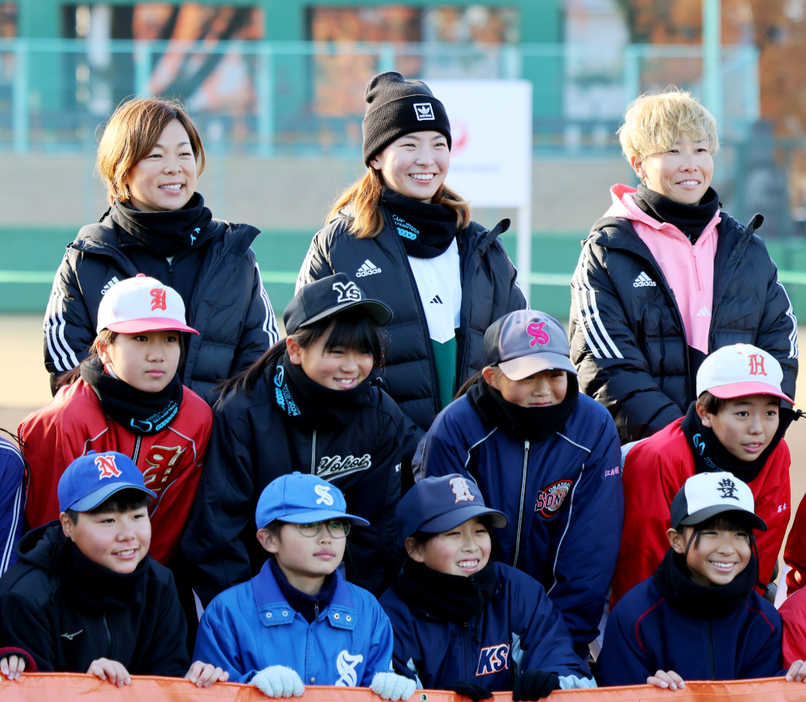 子どもたちと笑顔で写真に納まる渋野選手（後列中央）。後列の左は原田さん、右は山田さん＝岡山県営球場