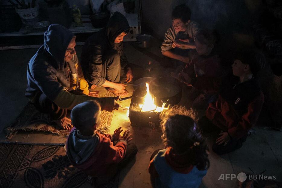 ガザ地区北部ガザ市で、料理の火を囲む男性と子どもたち（2024年12月11日撮影）。【翻訳編集】 AFPBB News