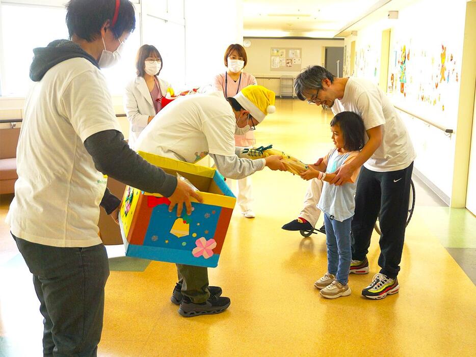 子どもにプレゼントを渡す同会メンバーの榮島四郎さん