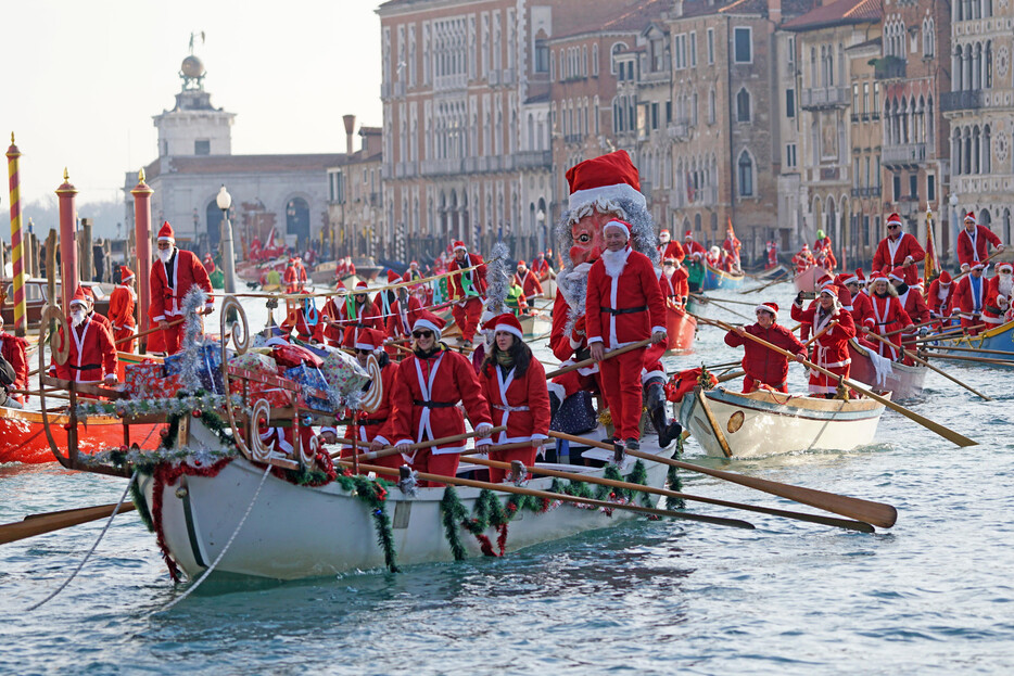 ２２日、イタリア北部の「水の都」ベネチアで、名物のゴンドラをこぐサンタクロース一同。ゴンドラで大運河を渡る伝統的イベントの一こまで、約２００人がサンタクロースに扮（ふん）し、水上を行進した。