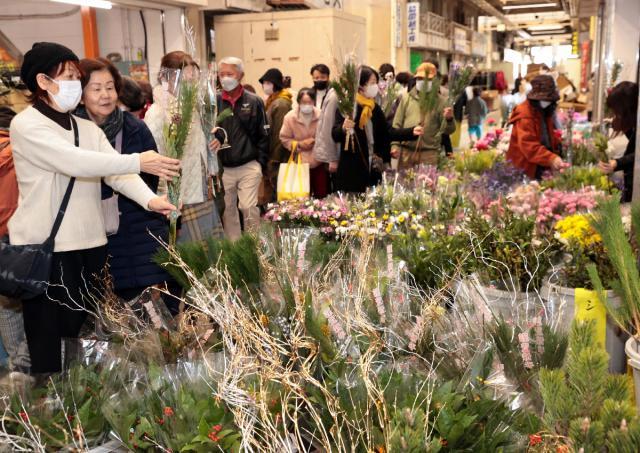 正月用の飾り花を買い求める客でにぎわう宮崎市中央卸売市場の関連店舗商店街＝２１日午前