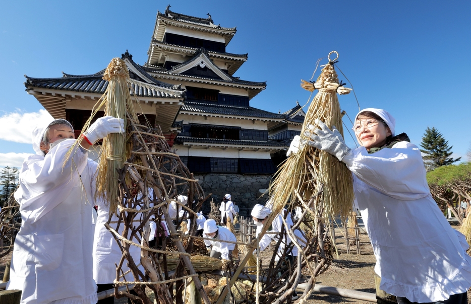 ボタンに「わらぼっち」をかぶせる古城会婦人部の会員