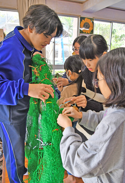 網でできたリースに飾りをつける児童ら（21日、宇検村の平田公民館）