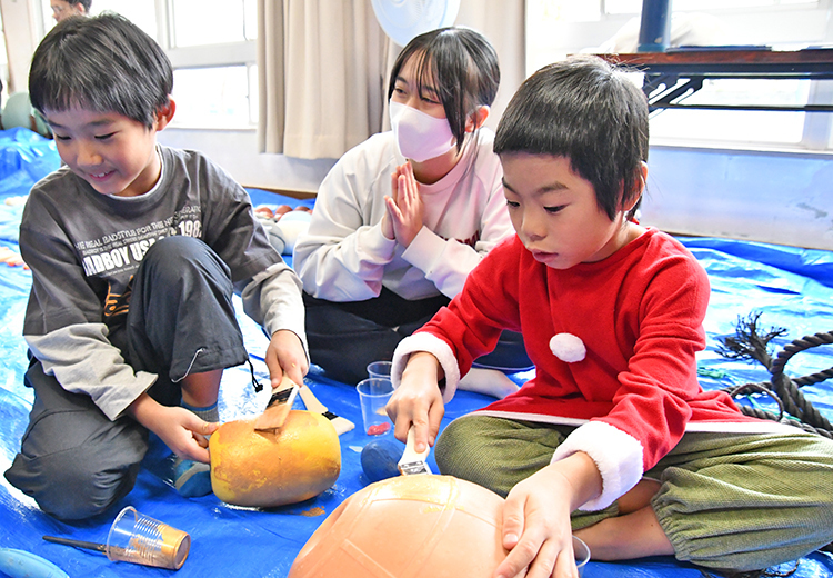 奄美高生と一緒に海洋プラスチックに装飾する児童ら（21日、宇検村の平田公民館）