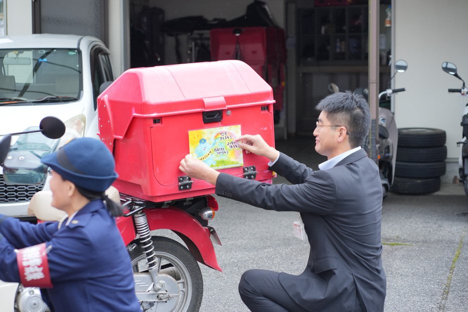 バイクにステッカーを貼る藤井局長