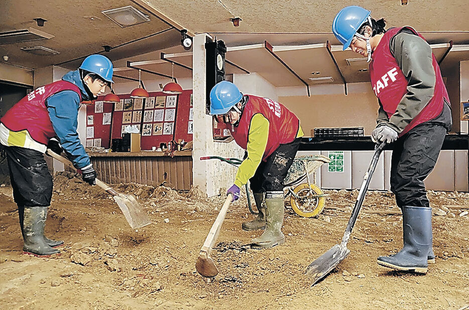 土砂のかき出し作業に励む３人＝珠洲市真浦町