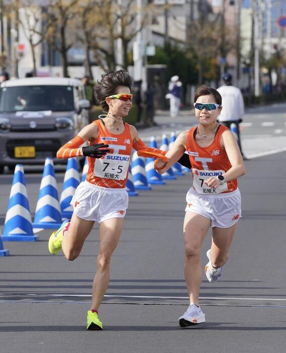 富士山女子駅伝　中継場で拓大6区門脇奈穂（右）にたすきを渡す5区不破聖衣来（左）（撮影・垰建太）